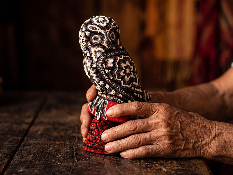 Wixáritari artisan holding an owl that he completed, stunning artwrok.
