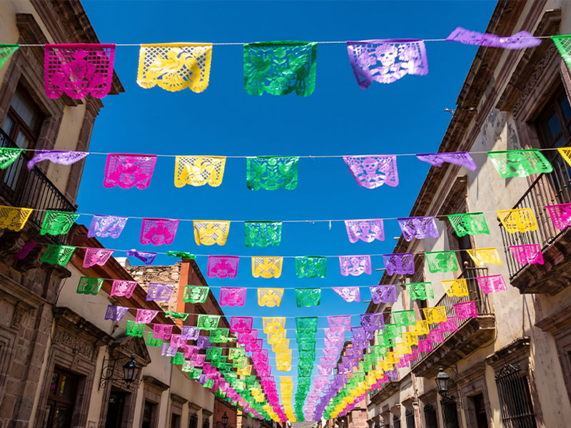Rows of multicoloured papel picado banners strung across a street in San Salvador Huixcolotla, Puebla