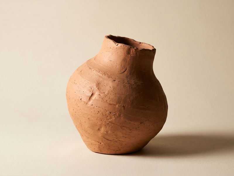 A uniquely shaped, hand-formed ceramic vessel with an irregular silhouette, photographed alone